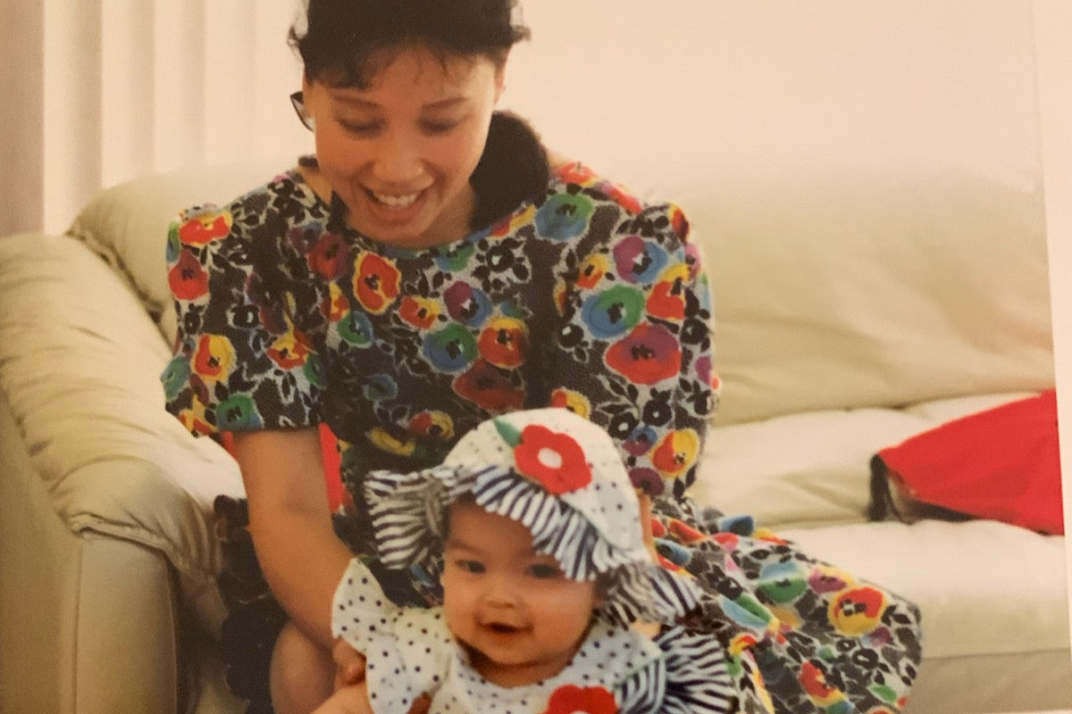 Woman and baby in floral and polka dot outfits standing in a living room.