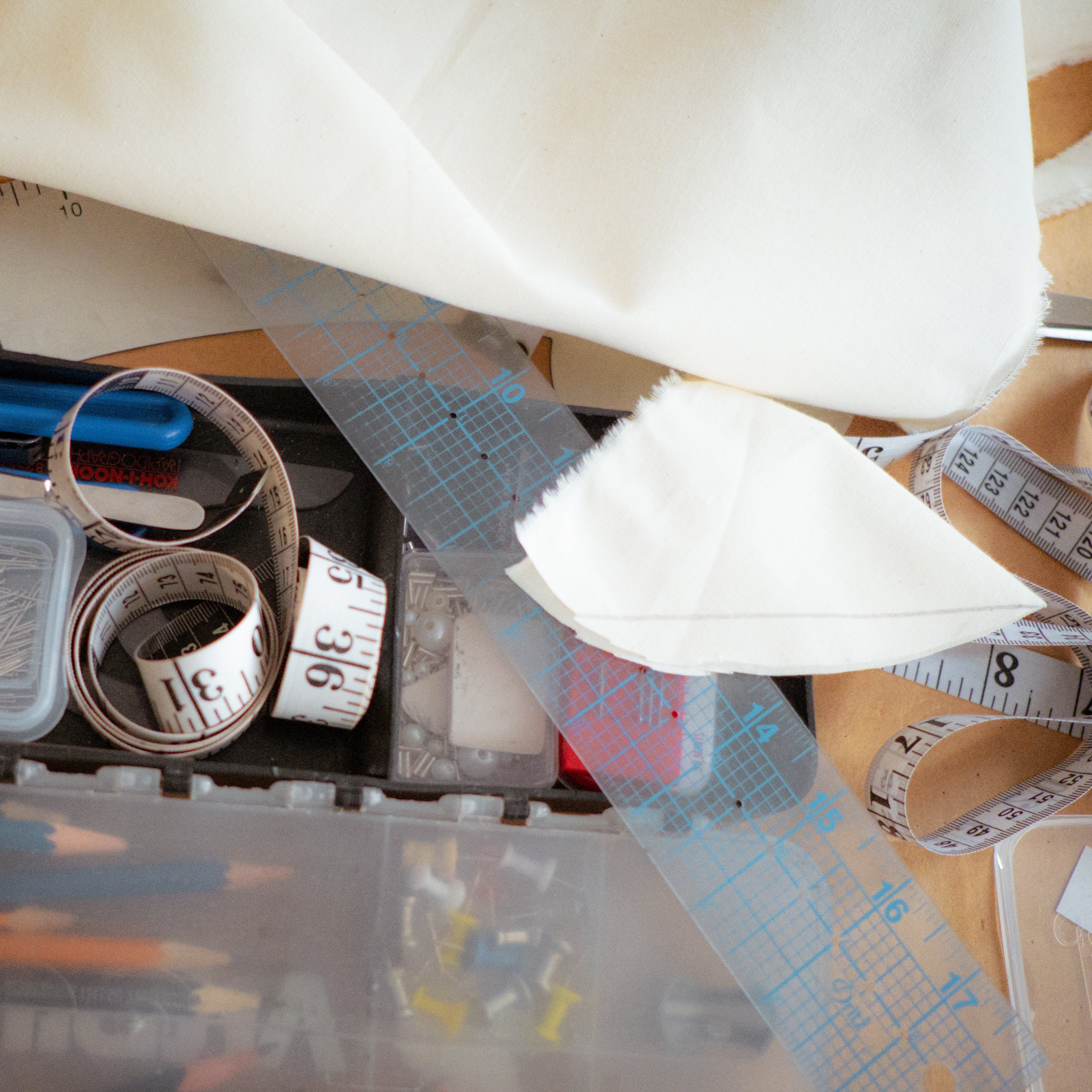 Crafting tools including scissors, measuring tapes, and a ruler on a table with fabric.