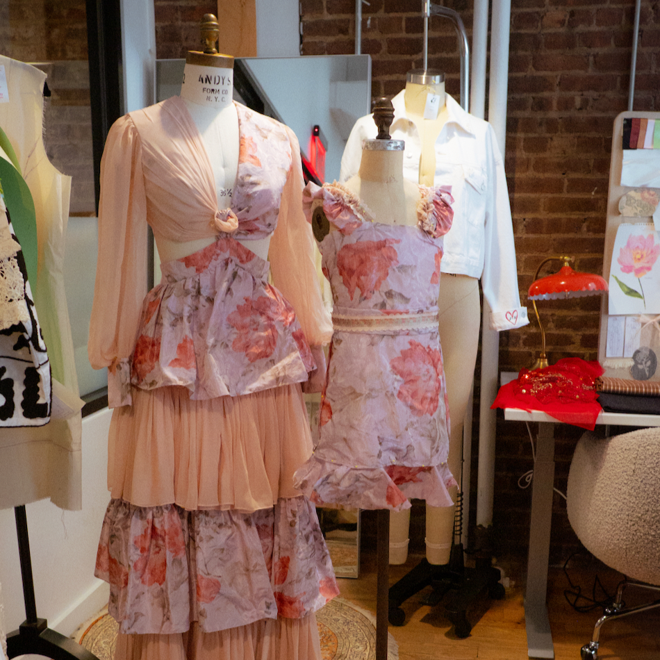Two mannequins wearing floral dresses in a bespoke studio